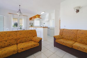 Una sala de estar con dos sofás, un área de cocina y un comedor con una mesa y sillas.