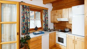 A compact kitchen with wooden cabinets, a white refrigerator, and a built-in oven. - Lovely apartment in villa for 4 guests with pool, WIFI, TV, terrace and pets allowed (Schlierbach)