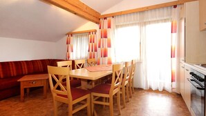 A dining area with a wooden table and chairs, a sofa, and a kitchen with an oven. - Lovely apartment in villa for 7 guests with WIFI, TV, terrace, pets allowed and panoramic view (Fügen)