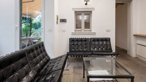 Un espace d’attente moderne, doté de canapés en cuir, d’une table en verre et d’une fenêtre donnant sur un paysage verdoyant.