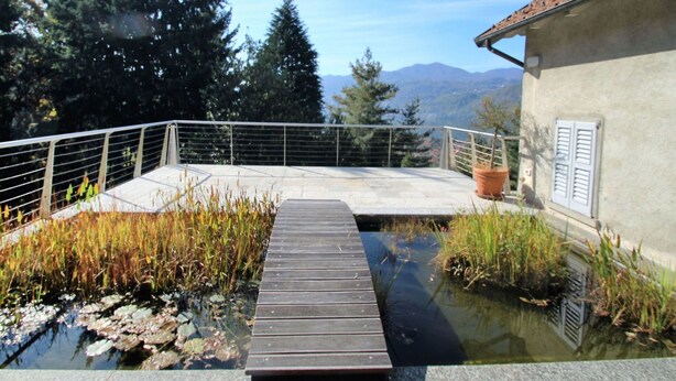 Une terrasse en bois surplombant un étang, avec vue sur les montagnes.