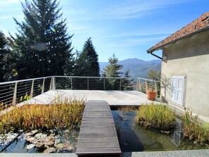Una terraza de madera sobre un estanque, con vistas a montañas.