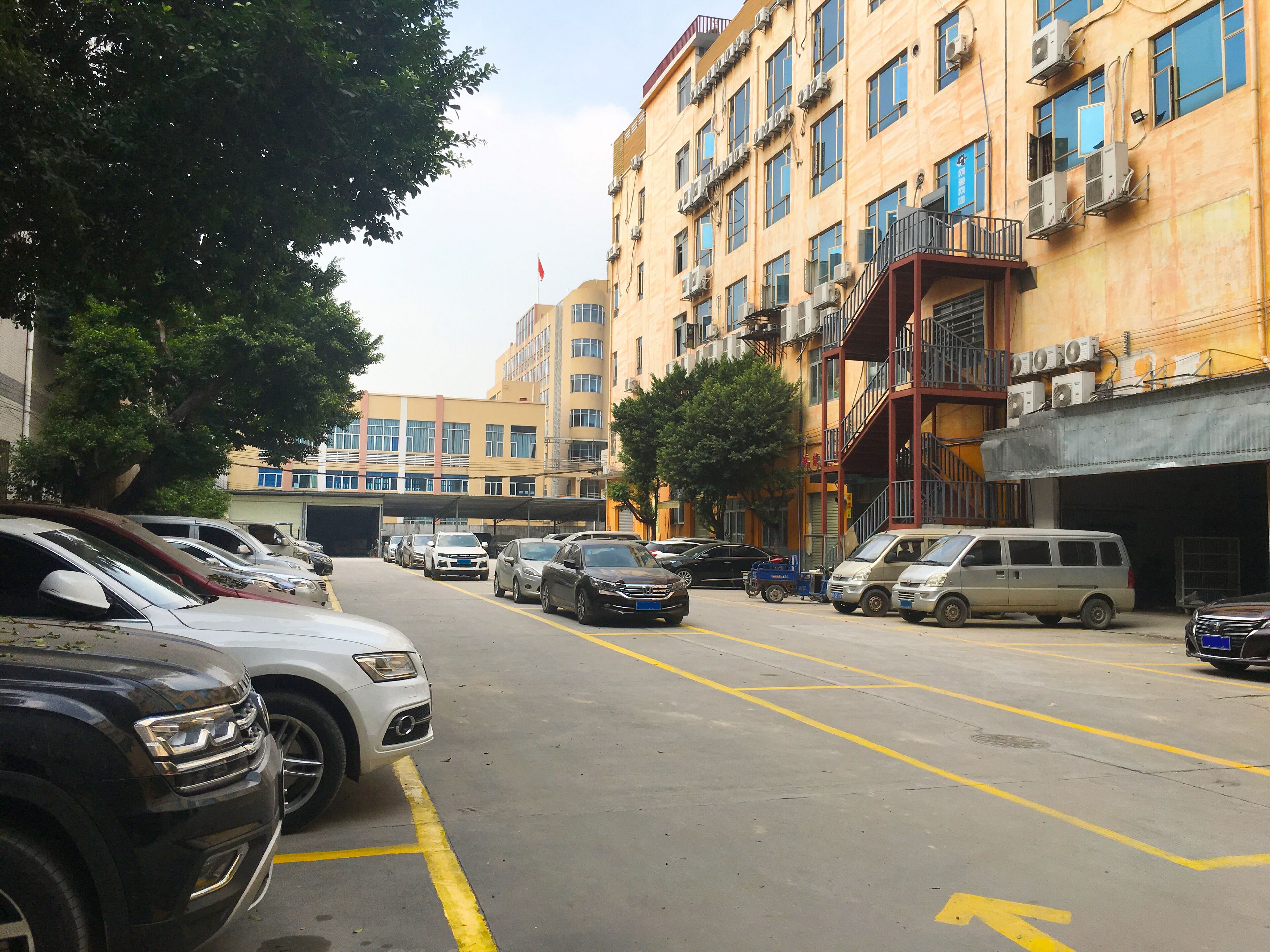 Un parking rempli de voitures et un immeuble doté de balcons et de climatiseurs.