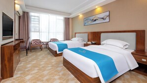 Habitación de hotel con dos camas, televisión, escritorio y una silla.