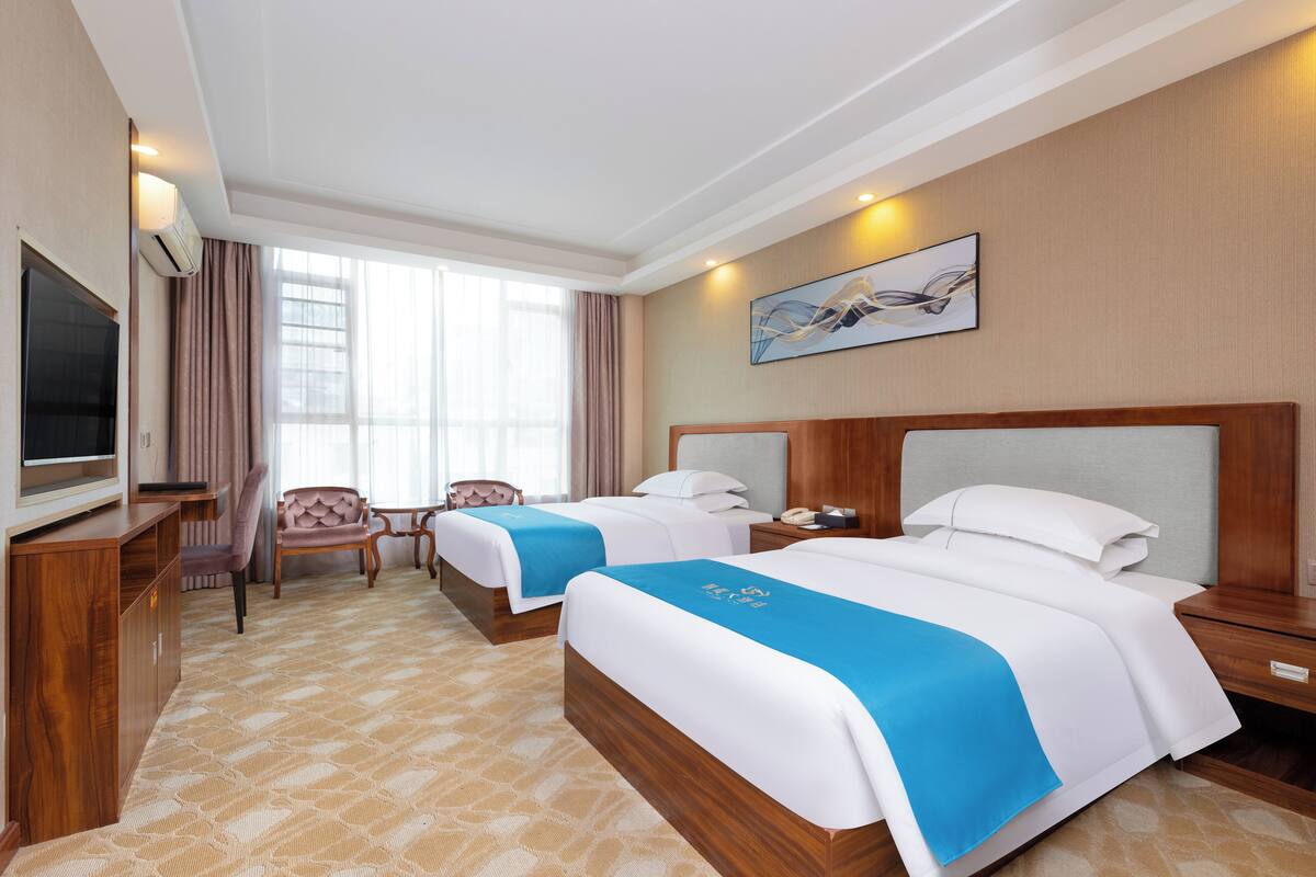 Een hotelkamer met twee bedden, een televisie, een bureau en een stoel.