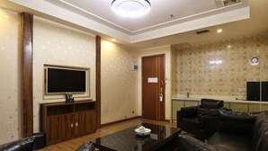 Una sala de estar con televisor de pantalla plana, sofás de cuero, una mesa de centro y una cocina con fregadero y encimera.