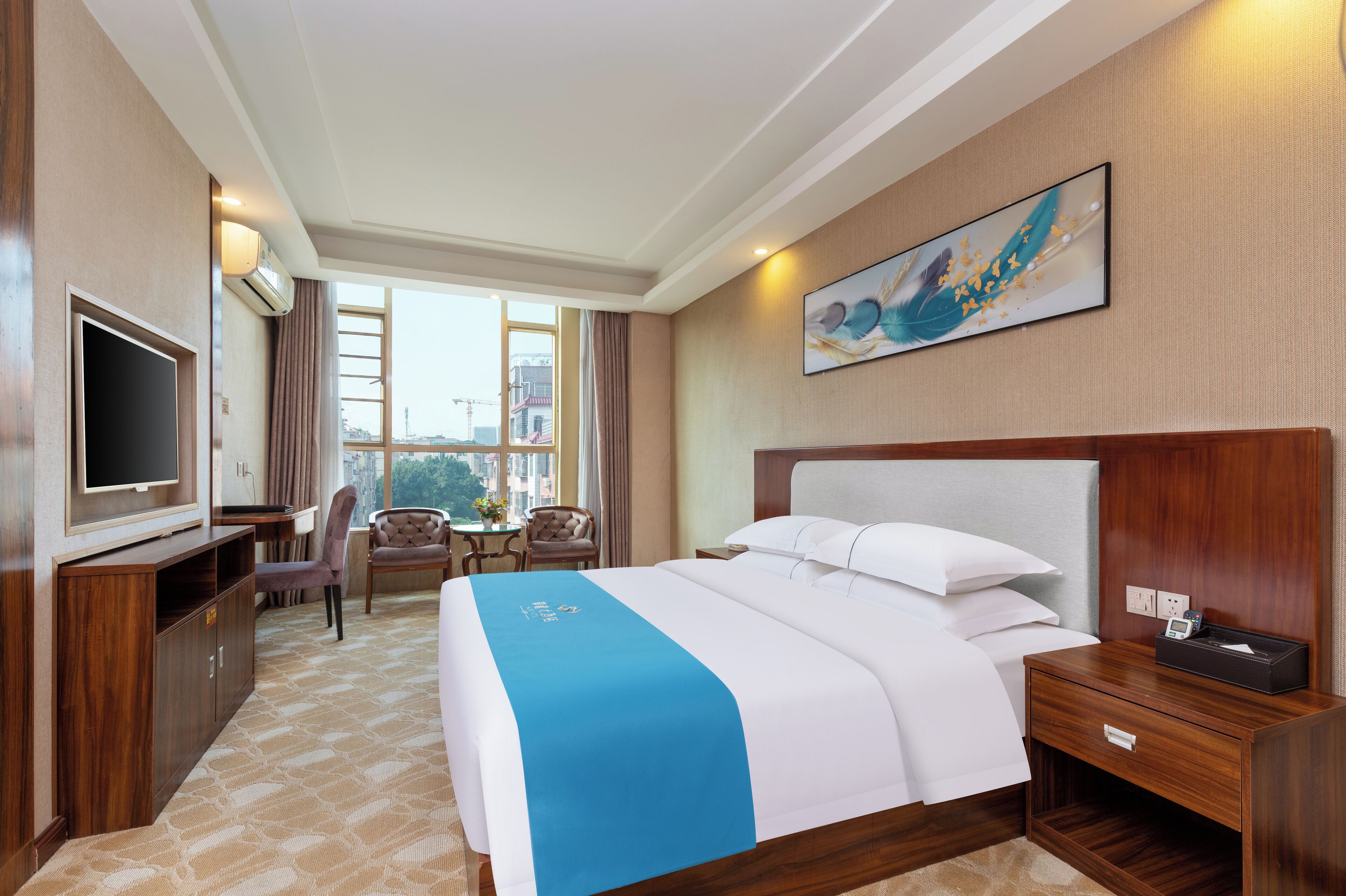 A hotel room with a large bed, a TV, a desk, and a chair.