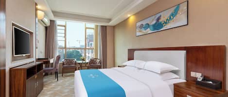 Una habitación de hotel con una cama grande, televisión, escritorio y silla.