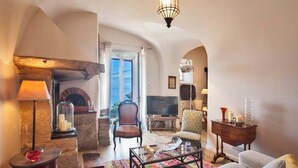 A cozy living room with a stone fireplace, a television, and comfortable seating. - Villa A Ventosa (Bastia)