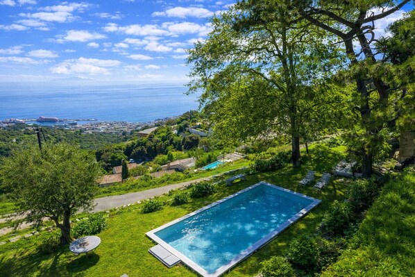 A rectangular pool with a clear view of the ocean and a lush green landscape. - Villa A Ventosa (Bastia)