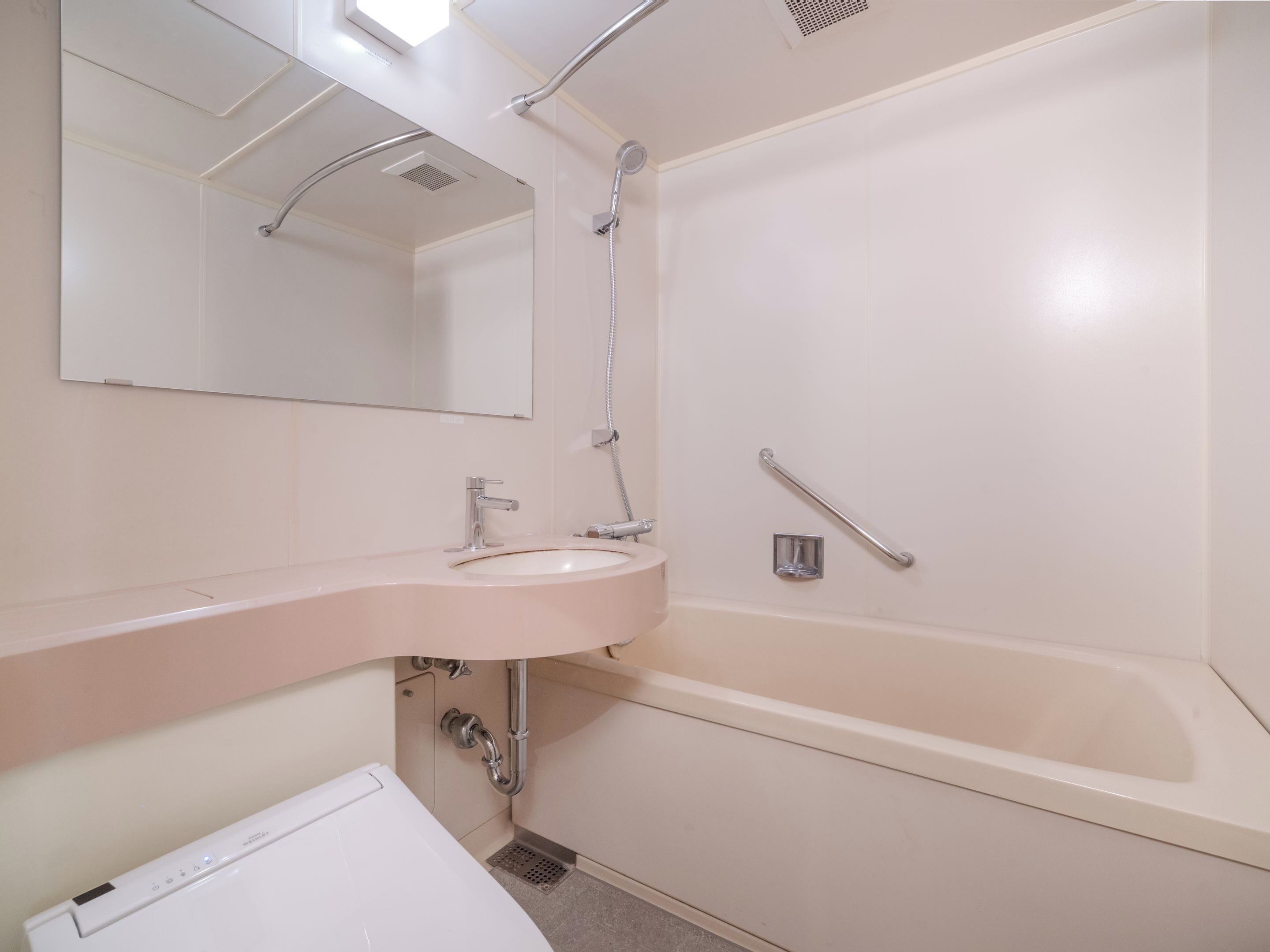 Un baño con lavamanos, espejo y bañera blancos.