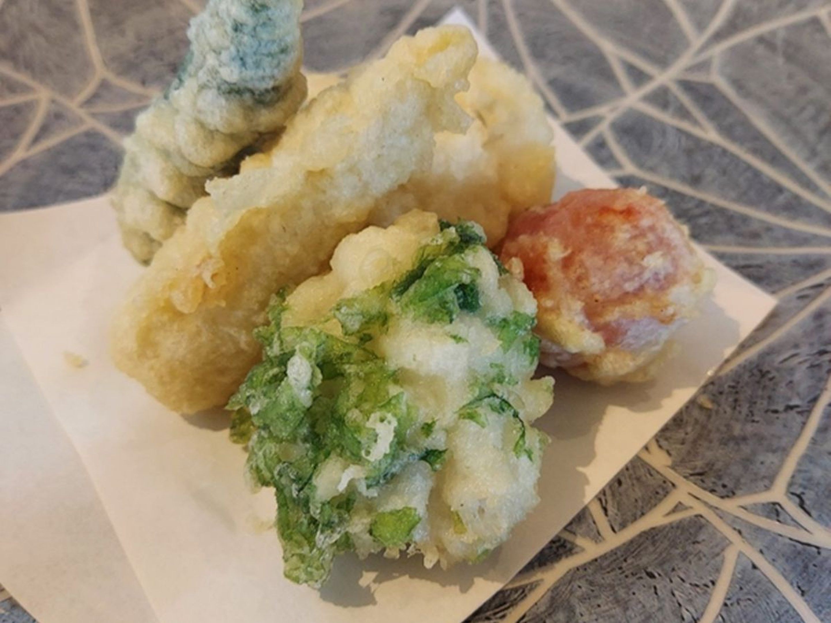 A plate of food with various items including a breaded item, a green vegetable, and a round item.