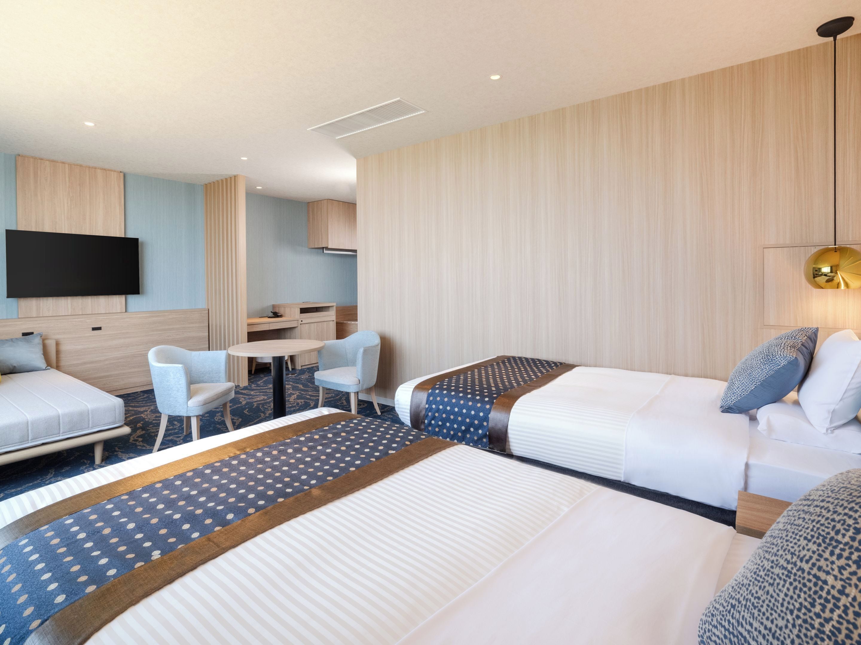 A hotel room with two beds, a desk, a chair, and a television.