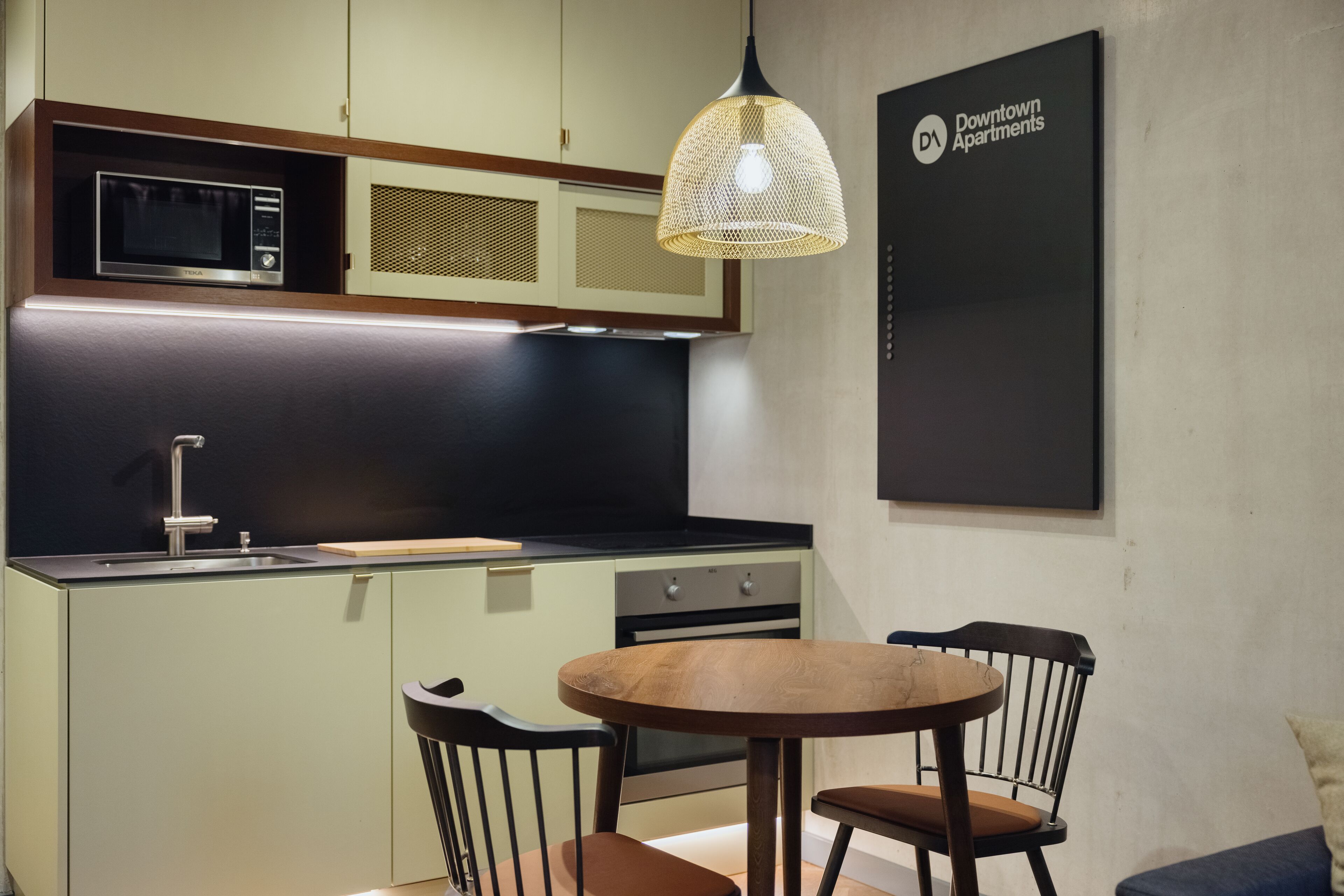 A modern kitchen with a microwave, sink, and dining area with chairs and a table.