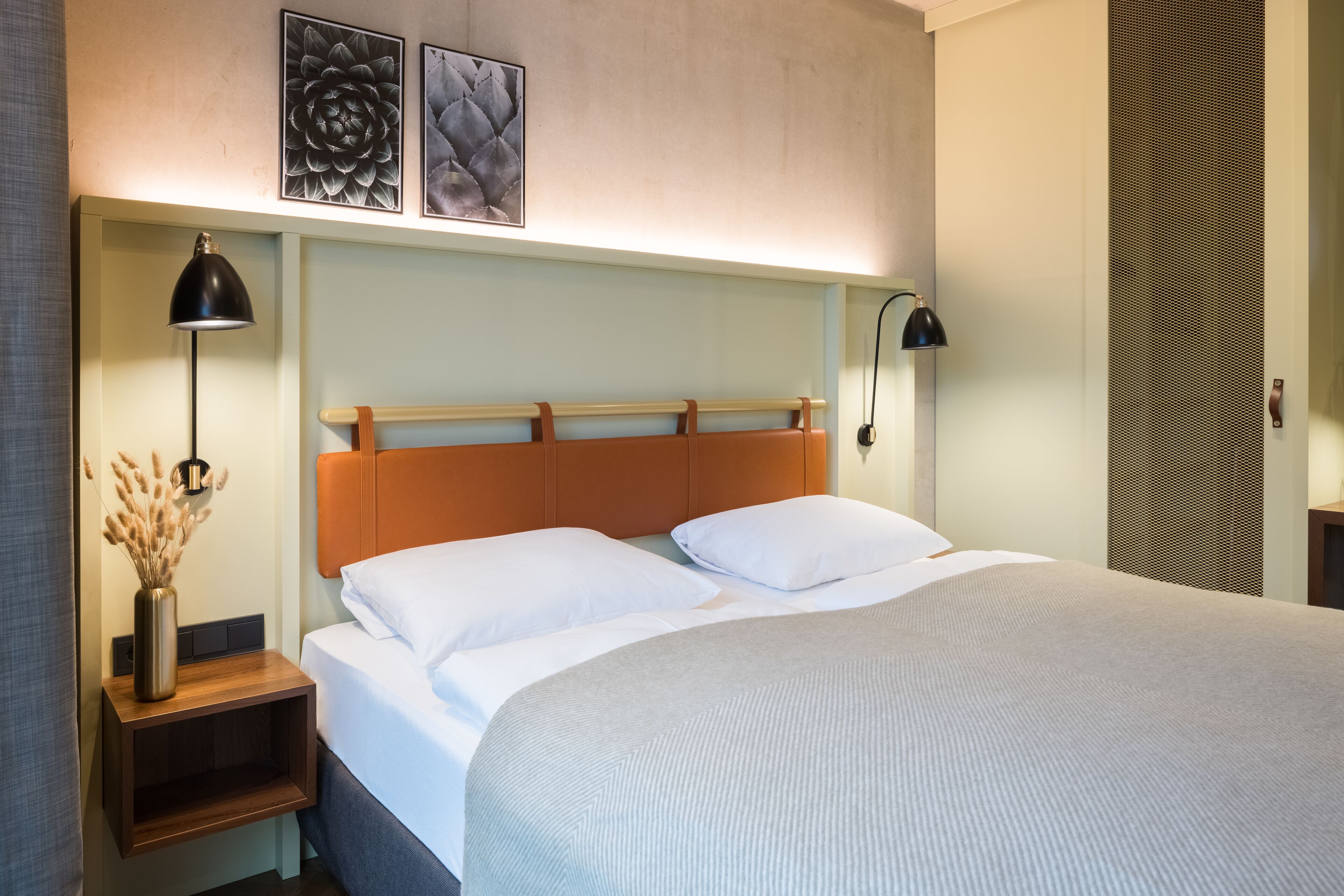 Un lit bien fait, avec du linge de lit blanc, une tête de lit en bois et deux lampes de chevet.