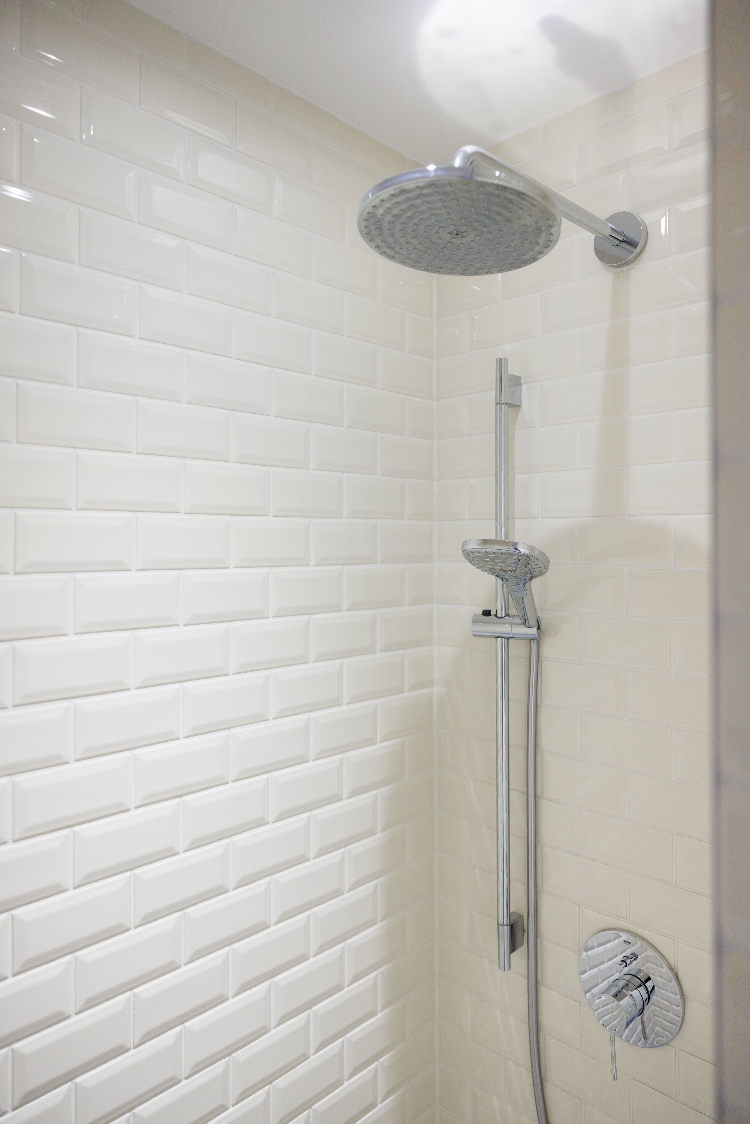 Eine Dusche mit Duschkopf und Bedienfeld an der Wand.