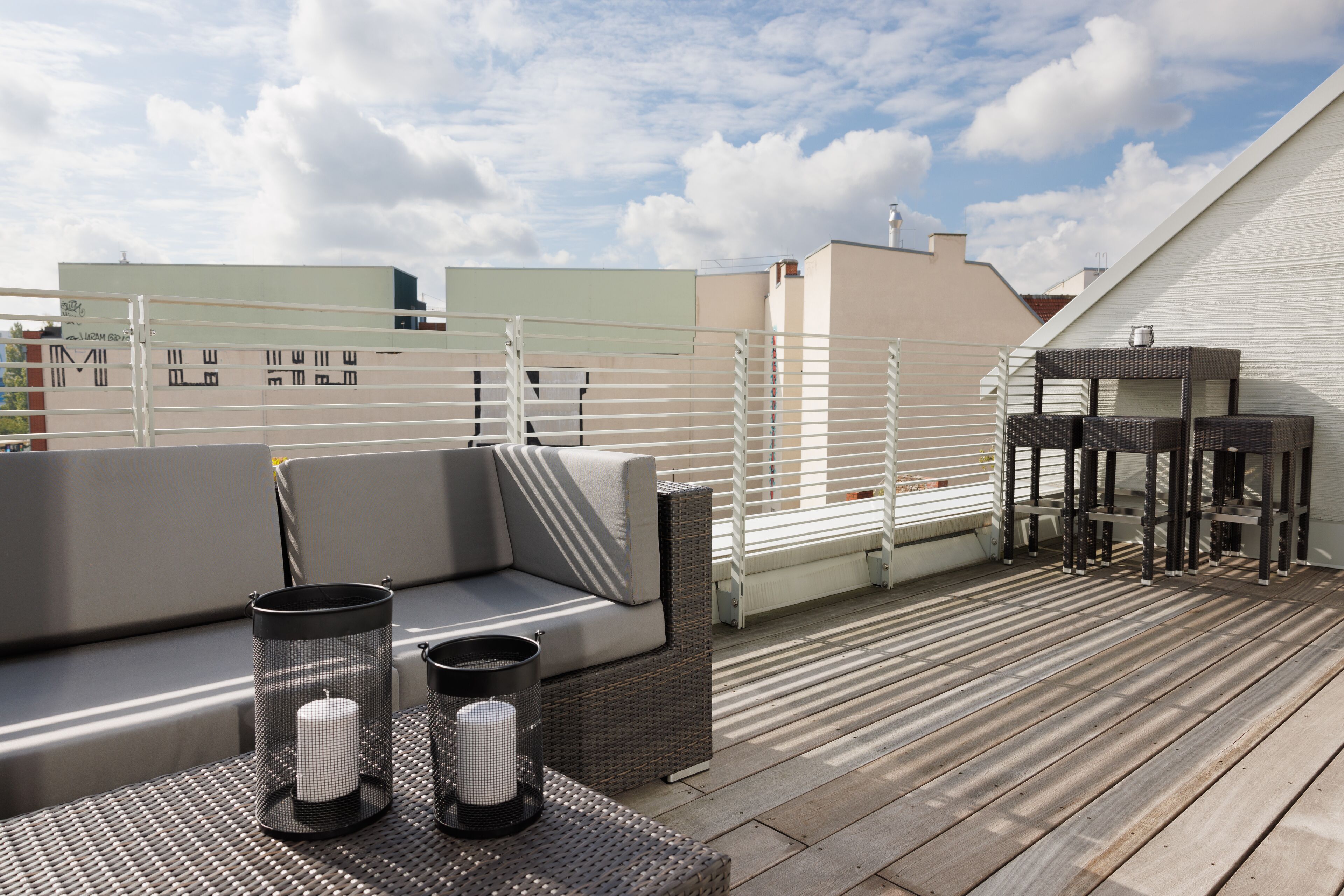 Terraço no telhado com sofá, dois castiçais e uma mesa pequena.