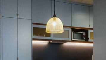 Una cocina moderna con una mesa redonda de madera y dos sillas, una lámpara colgante y electrodomésticos integrados.