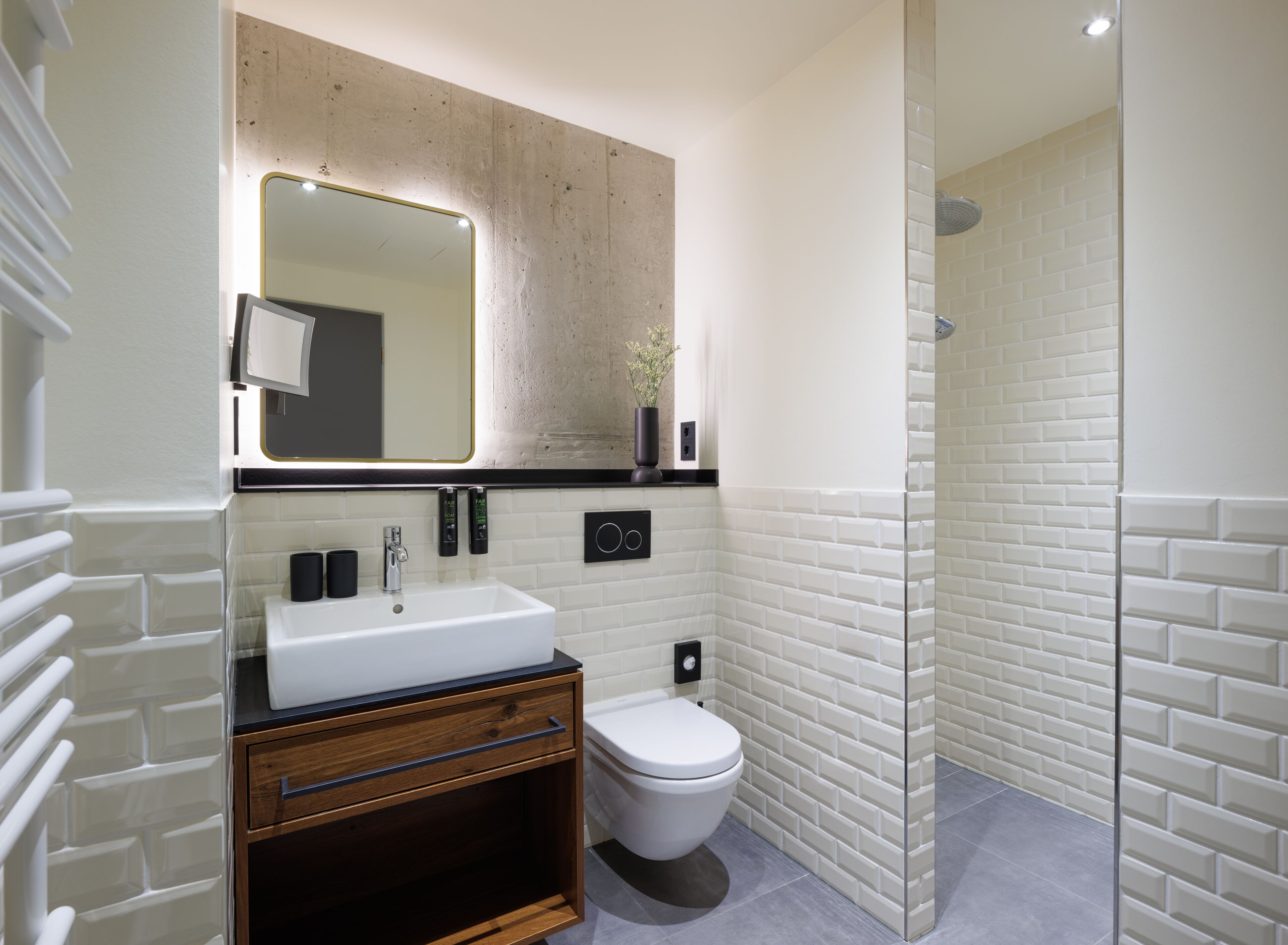 A modern bathroom with a white sink, a mirror, a toilet, and a glass-enclosed shower area.