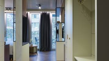 Un intérieur moderne avec un plancher en bois, un coin repas comprenant une table et des chaises, et une grande fenêtre agrémentée de rideaux.