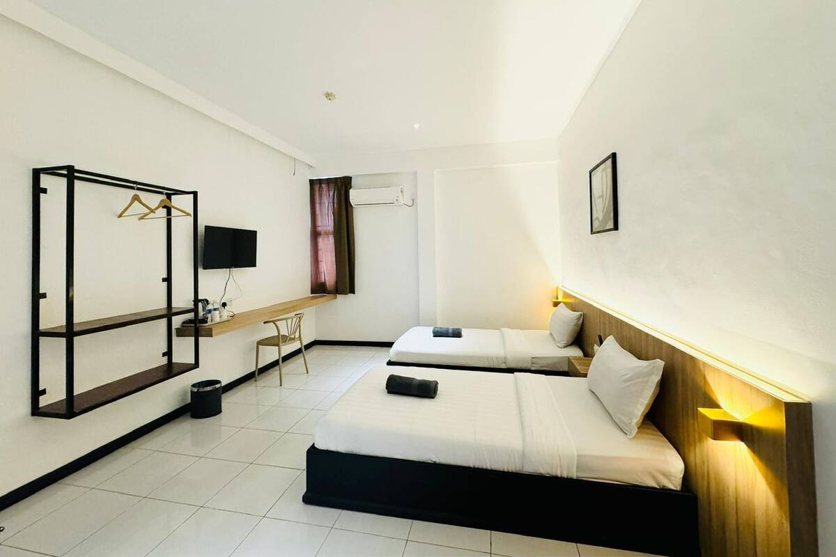 A hotel room with two beds, a TV, a desk, and a wardrobe.