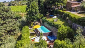 A pool area with lounge chairs and umbrellas, surrounded by lush greenery and stone walls. - Ridaldi by Interhome (Greve in Chianti)