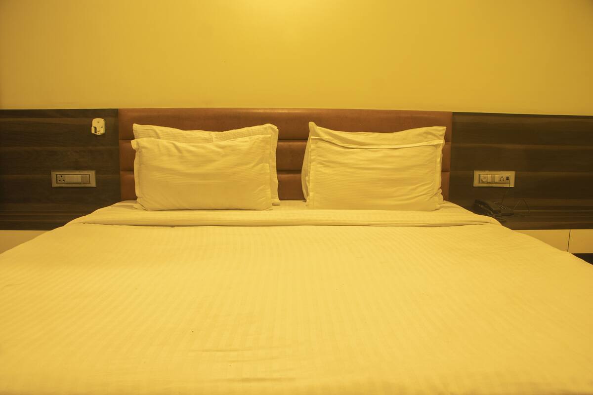 A bed with a headboard, two pillows, and a bedside table with a lamp.