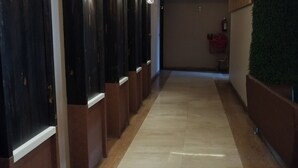 A hallway with dark wooden doors, a tiled floor, and a fire extinguisher on the wall. -  Hotel The Bentree, Bhopal (Bhopal)