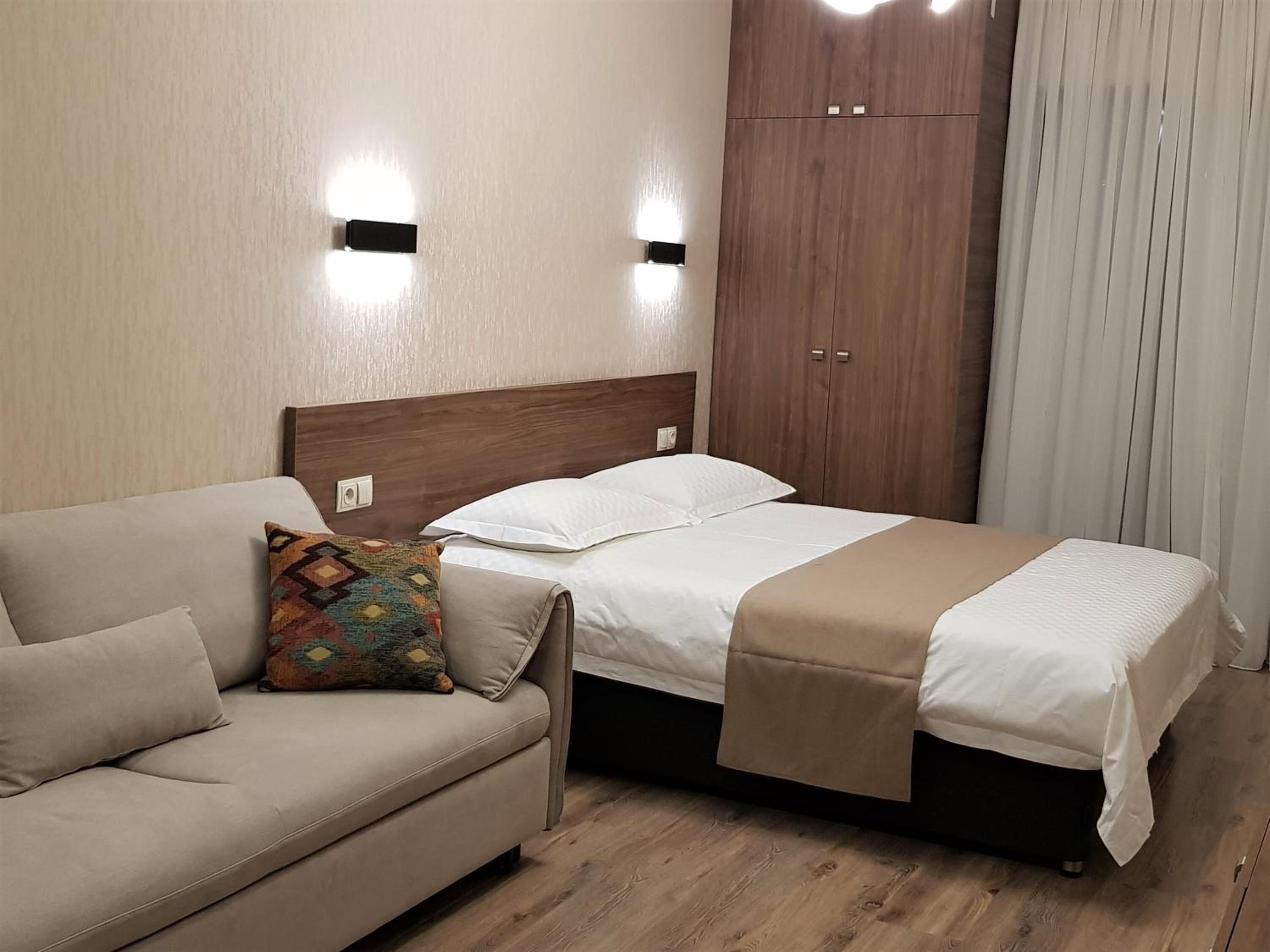 Una habitación de hotel con cama, sofá y armario.