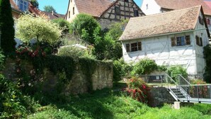 Una casa europea tradicional amb una paret de pedra i una escala que mena a l'entrada.