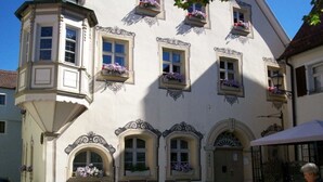 Un edifici europeu tradicional amb amuntaments decoratius, jardineres florals i un pati empedrat.