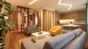 Una sala de estar moderna con un sofá, un sillón y una mesa de centro. Hay una zona de cocina con armarios de madera y una mesa de comedor.