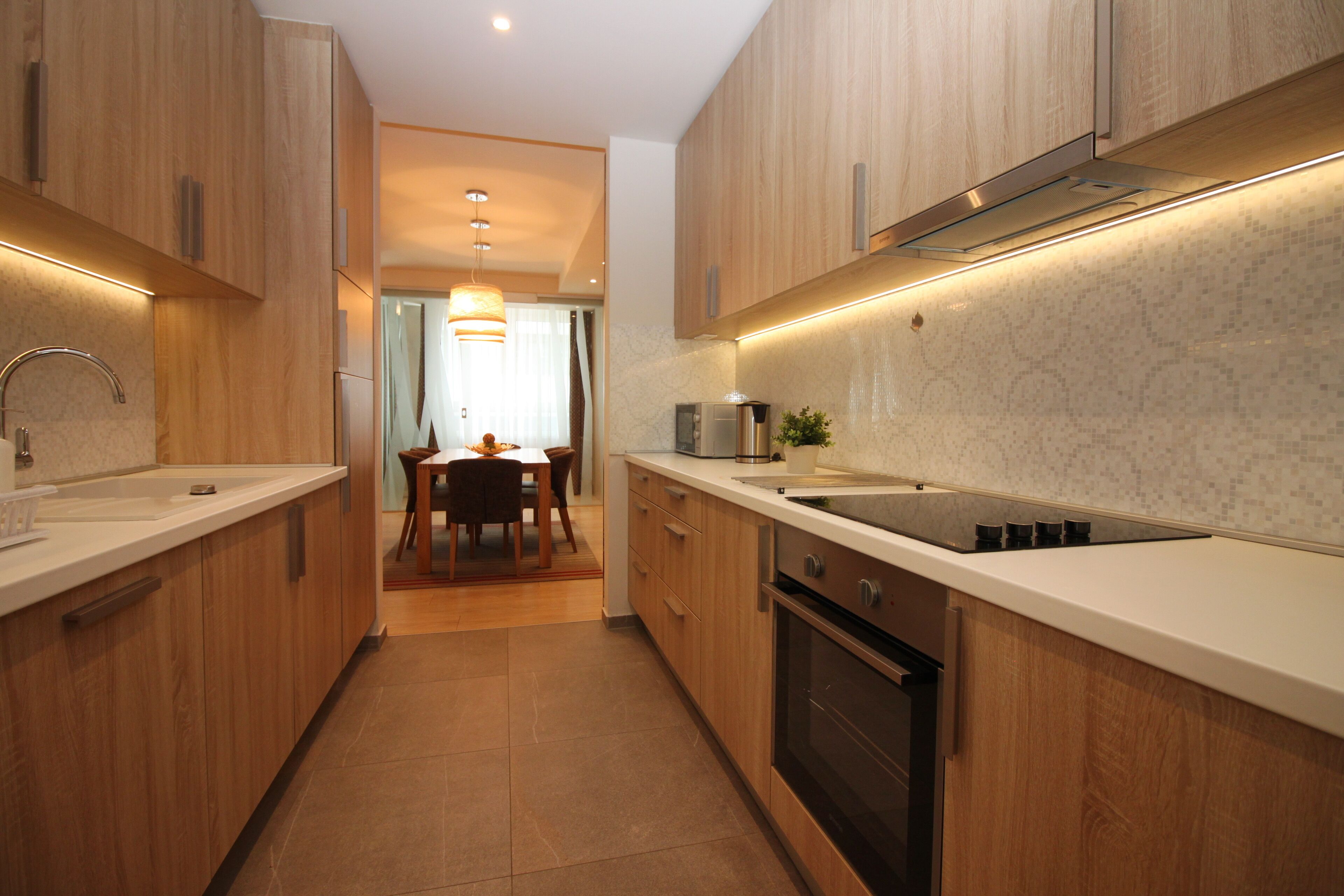 A modern kitchen with wooden cabinets, a stainless steel sink, and a built-in oven.