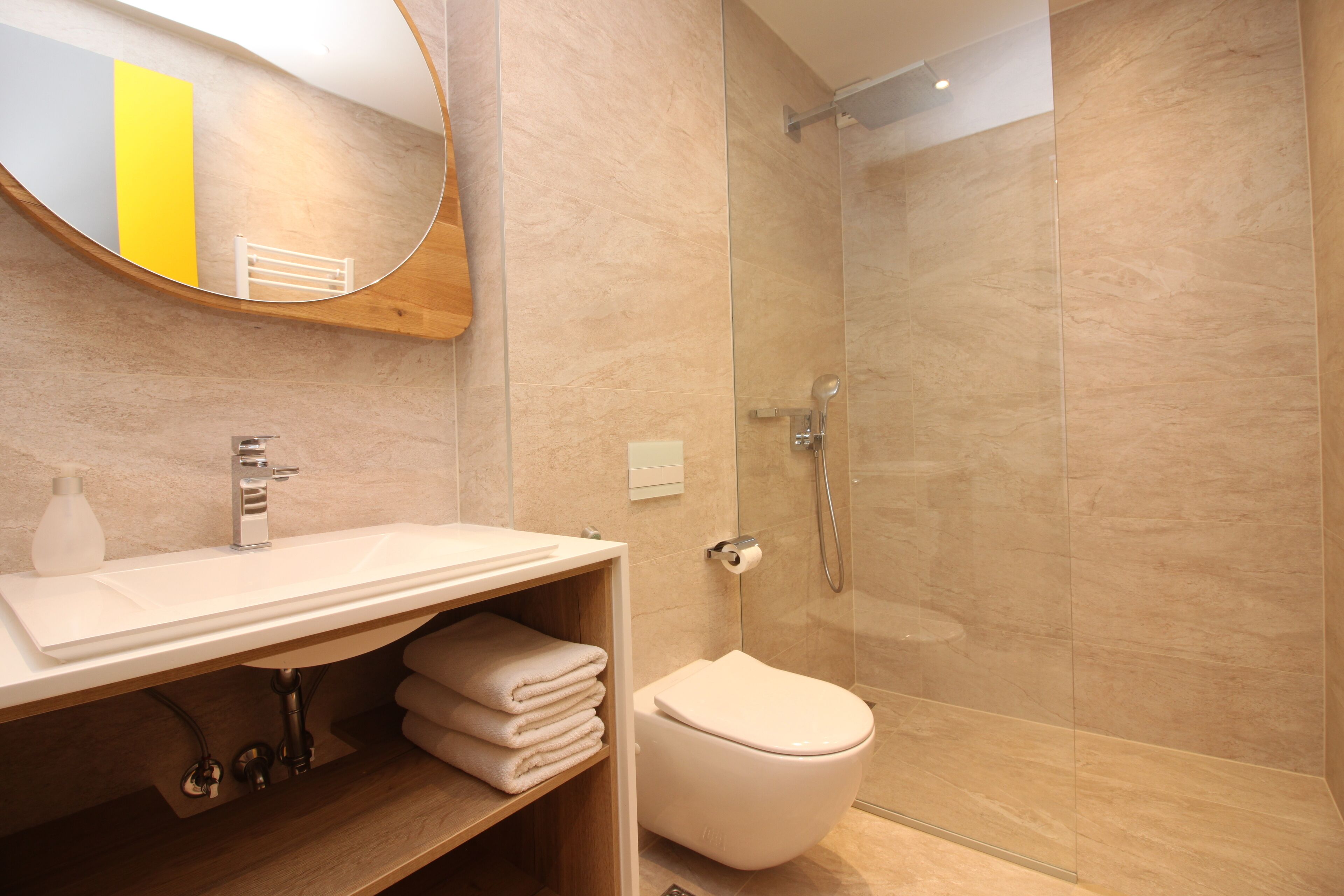 A modern bathroom with a glass-enclosed shower, a white sink with a mirror above, and a toilet.