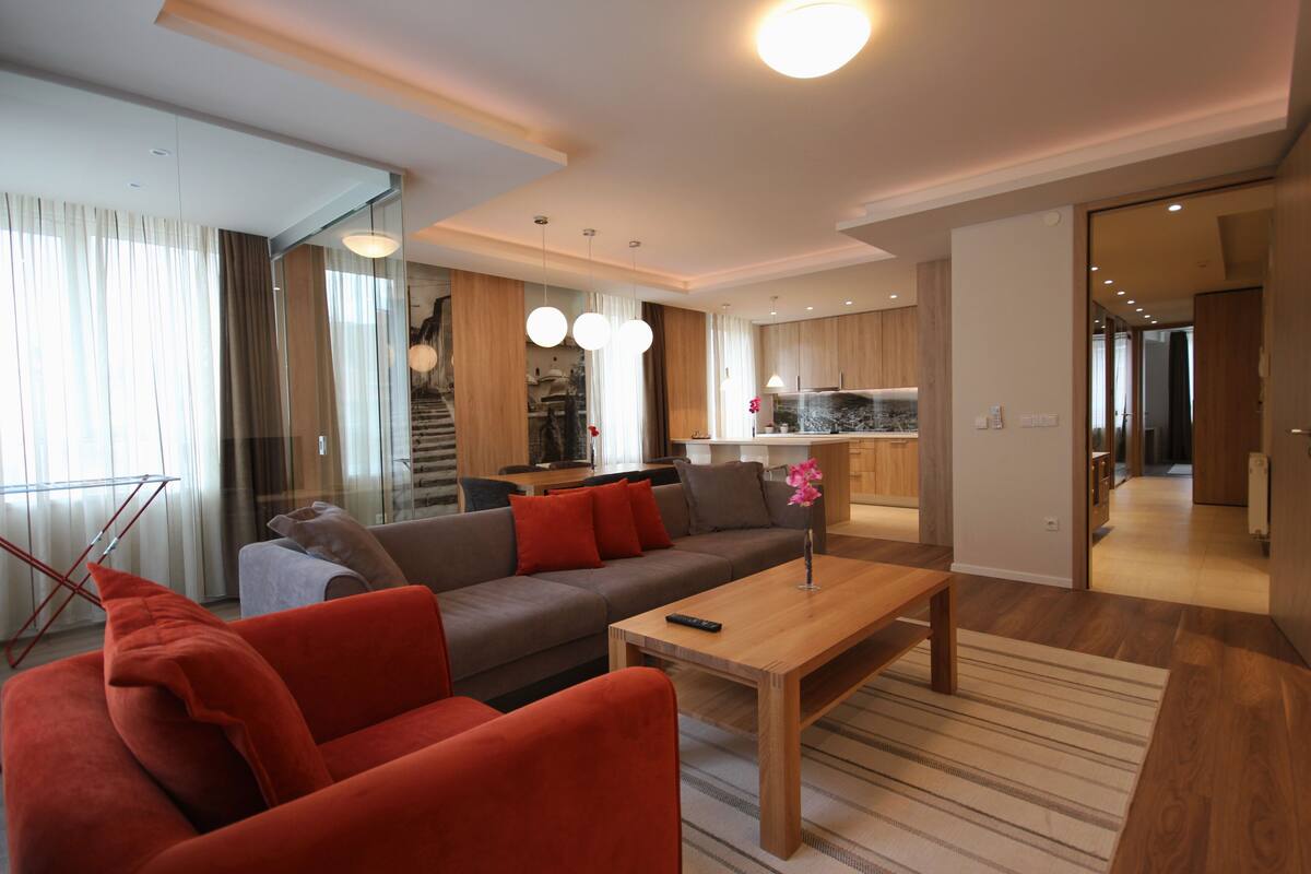 A modern living room with a sofa, a coffee table, and a kitchen in the background.