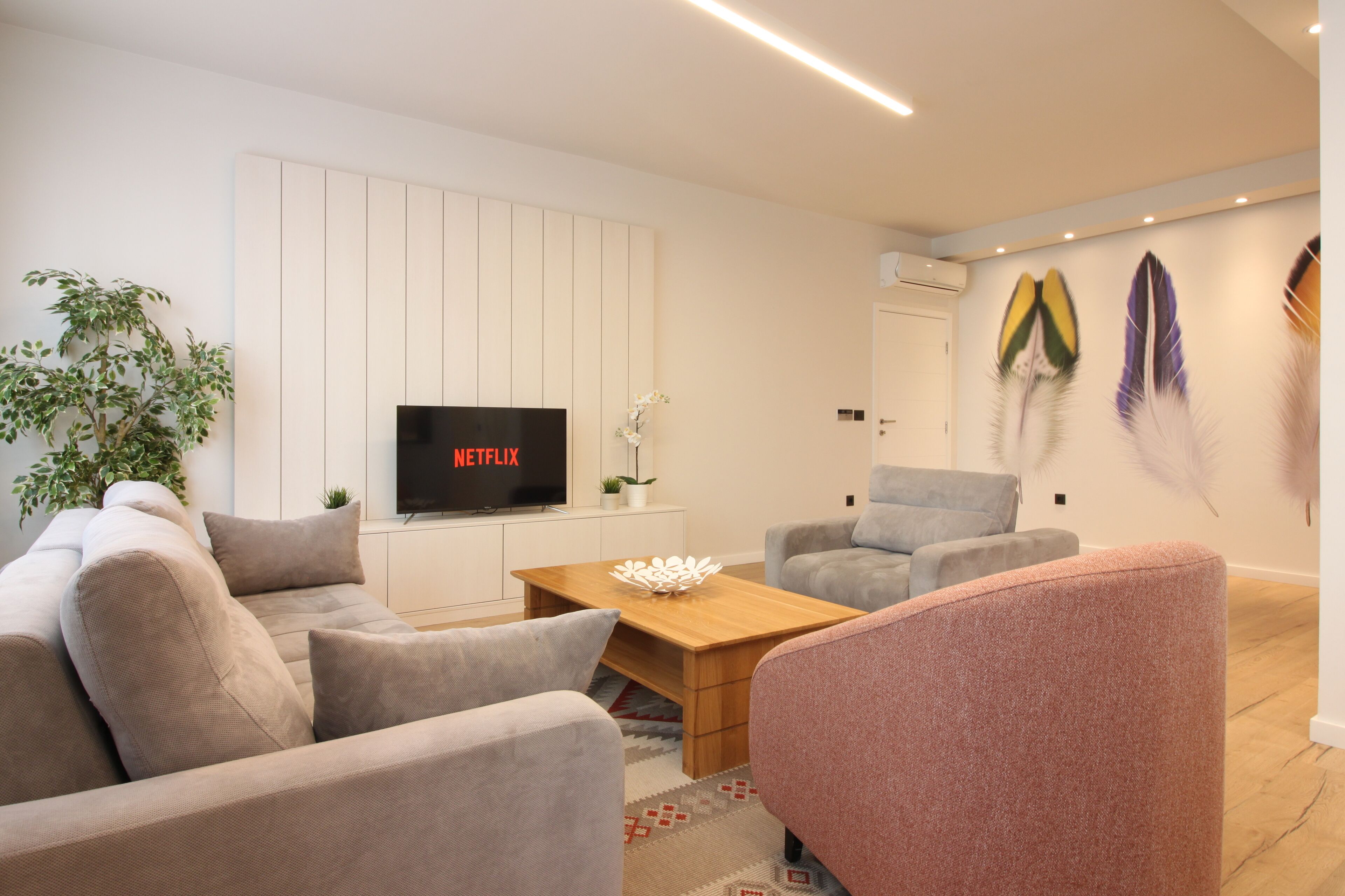 A modern living room with a sofa, armchairs, a coffee table, and a flat-screen TV.