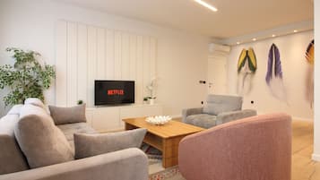 A modern living room with a sofa, armchairs, a coffee table, and a flat-screen TV.