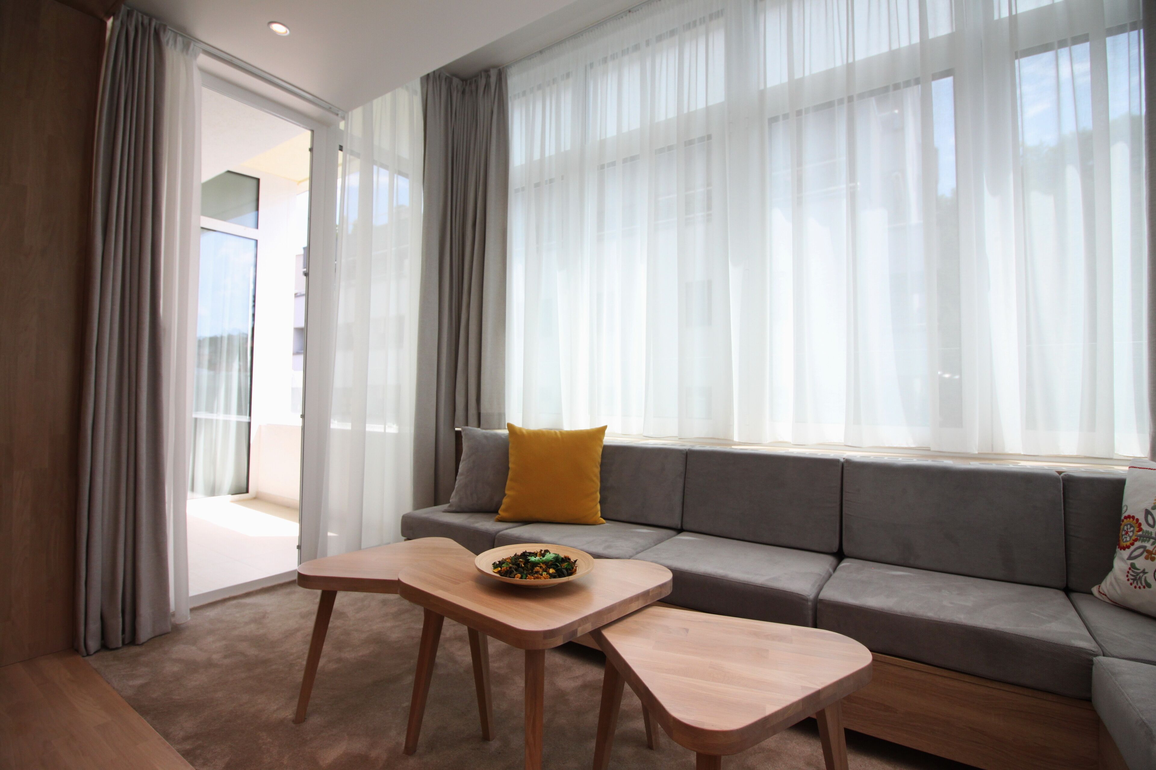 A modern living room with a sofa, a wooden table, and a bowl of fruit.