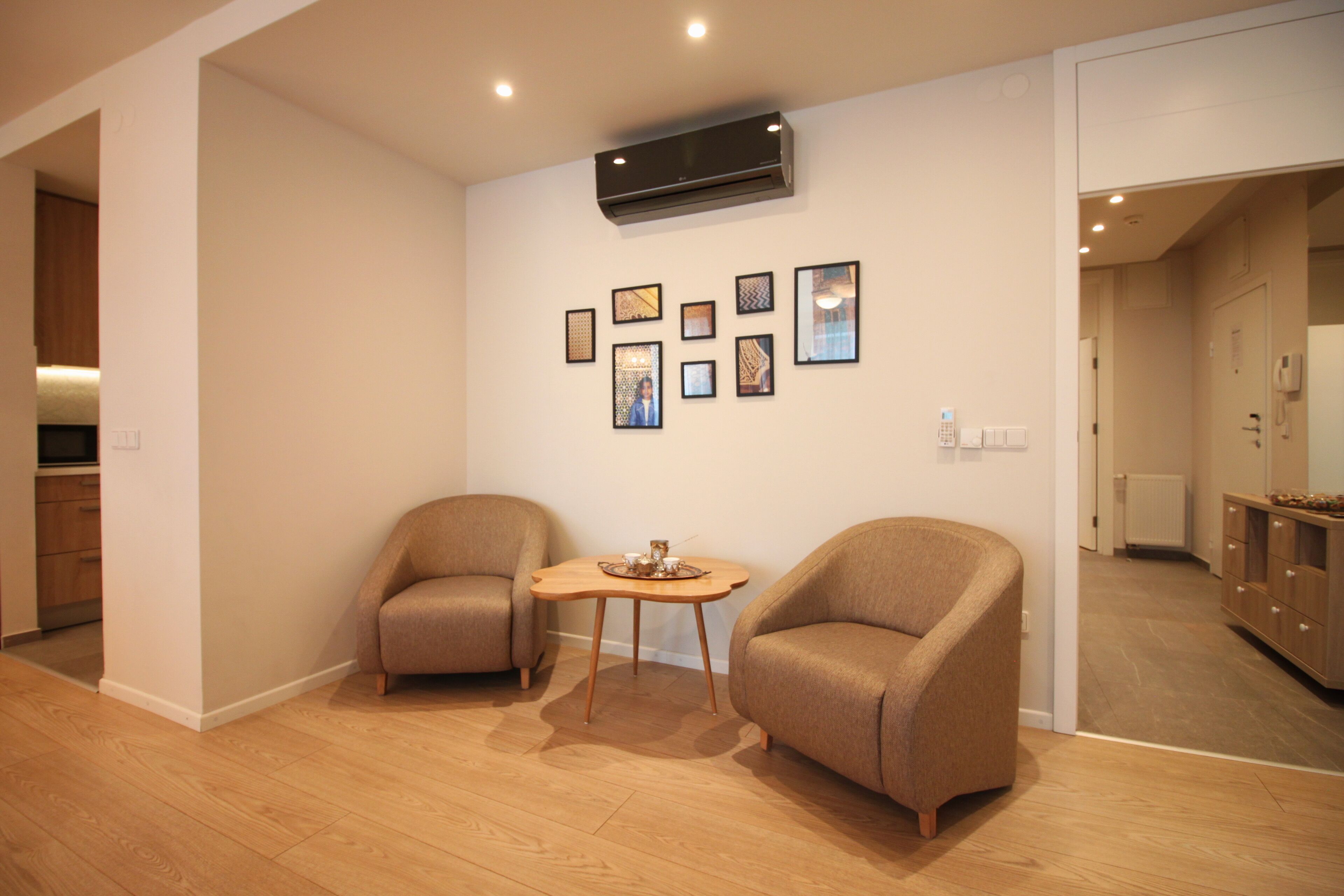 A modern living room with two armchairs, a small wooden table, and a wall-mounted air conditioner.