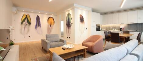 Una sala moderna con un sofá, sillones, una mesa de centro y un comedor con una mesa y sillas.