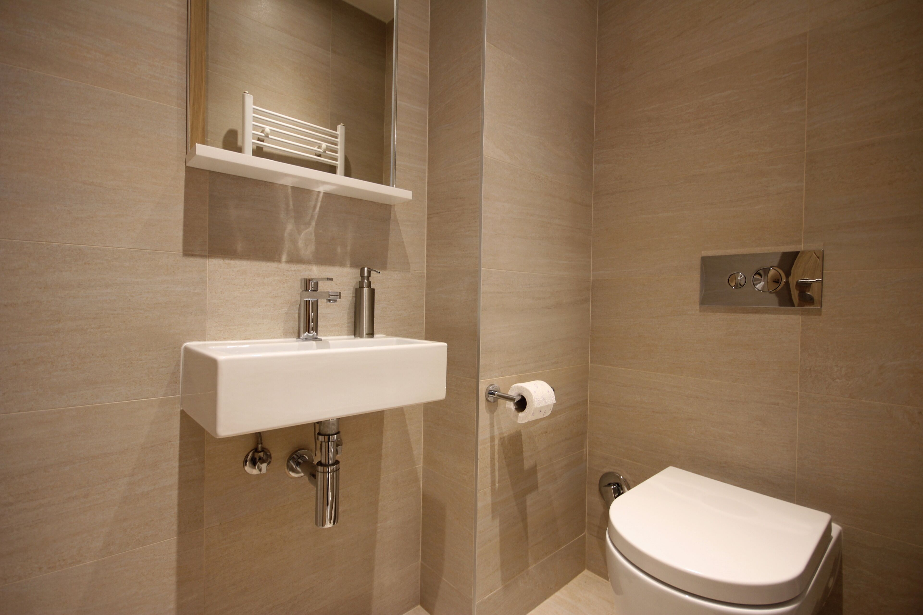 A modern bathroom with a white sink, a toilet, and a mirror above the sink.