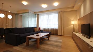 Un salon moderne comprenant un canapé, une table basse, un téléviseur et un coin repas avec des chaises et une table.