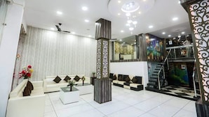 Un hall d’hôtel moderne avec un ensemble de canapés blancs, une table basse et un pilier décoratif.