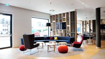 A modern lounge area with a sofa, chairs, and a TV.