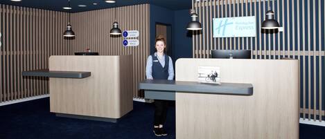 A reception desk area with a Holiday Inn Express sign, a general manager's nameplate, and a duty employee's nameplate.