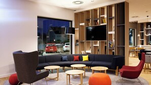 Una sala de estar moderna con un sofá modular, mesas redondas y un televisor grande.