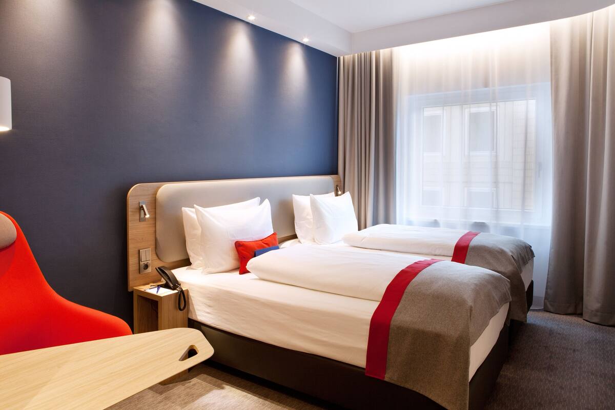 A hotel room with two beds, a desk, and a chair.