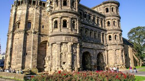 Un edificio histórico de piedra con múltiples arcos y columnas, que cuenta con una entrada central amplia y otras entradas más pequeñas a los lados.