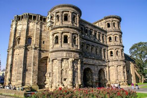 A historic stone building with multiple arches and columns, featuring a large central entrance and smaller side entrances.