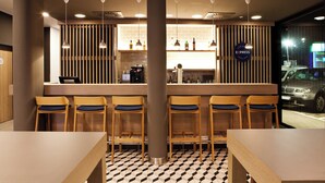 A modern bar area with wooden bar stools, a counter with a coffee machine, and a sign indicating it is an Express Cafe & Bar. - Holiday Inn Express Trier by IHG (Trier)